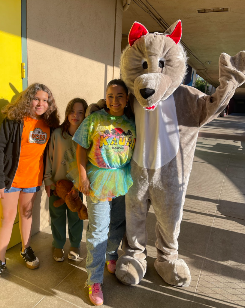 The VCES wolf waves with students and a teacher.